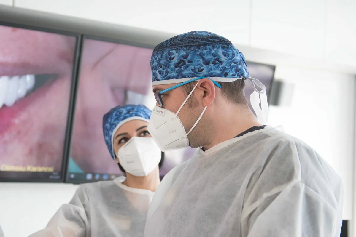 Doi medici Olidental Clinic analizează pe ecrane mari fotografiile zâmbetului unui pacient