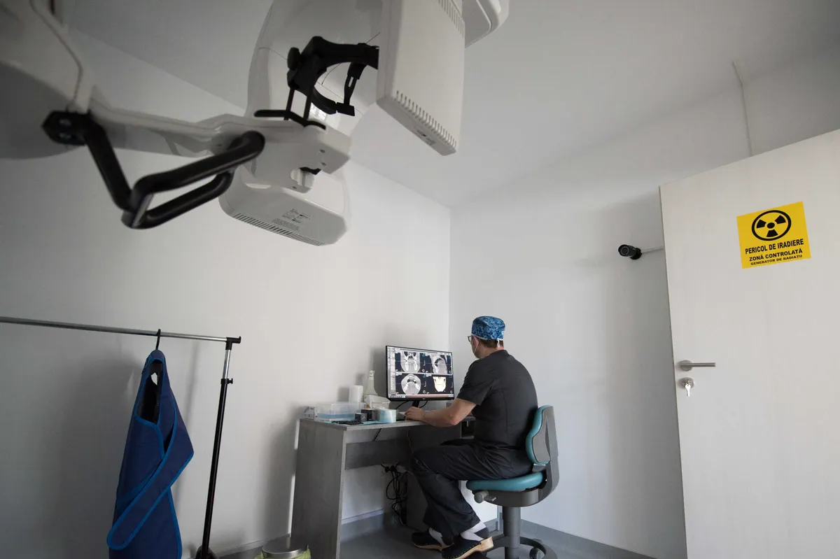 Camera de radiologie a Olidental Clinic: aparatul de imagistică dentară și un medic care analizează imagini 3D pe monitor